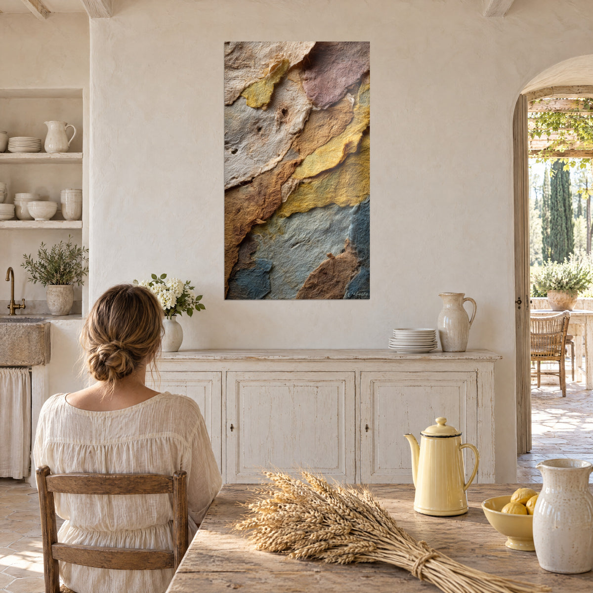 Quadro lamelle di carta fibrosa, giallo paglia e grigio azzurro, contro un muro color crema di fronte a una donna al tavolo della cucina