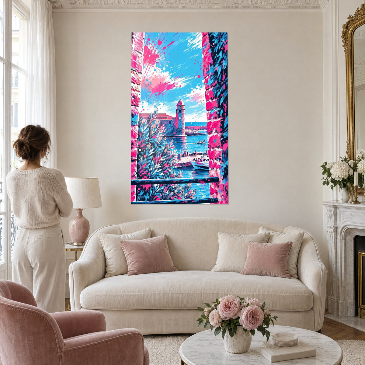 Cuadro campanario de Collioure en rosa y azul, enmarcado por una ventana en flor, mujer de espaldas, sobre un sofá en un salón luminoso
