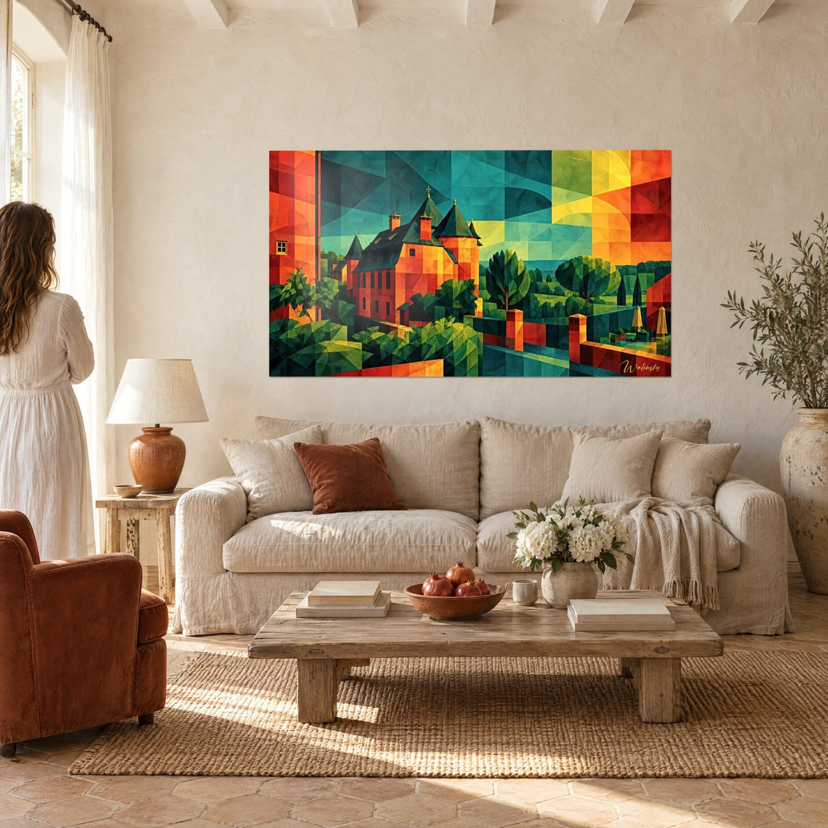 Schilderij middeleeuws kasteel met spitse gefacetteerde torentjes in oranje en dennengroen, een vrouw van achteren, boven een bank in een lichte woonkamer