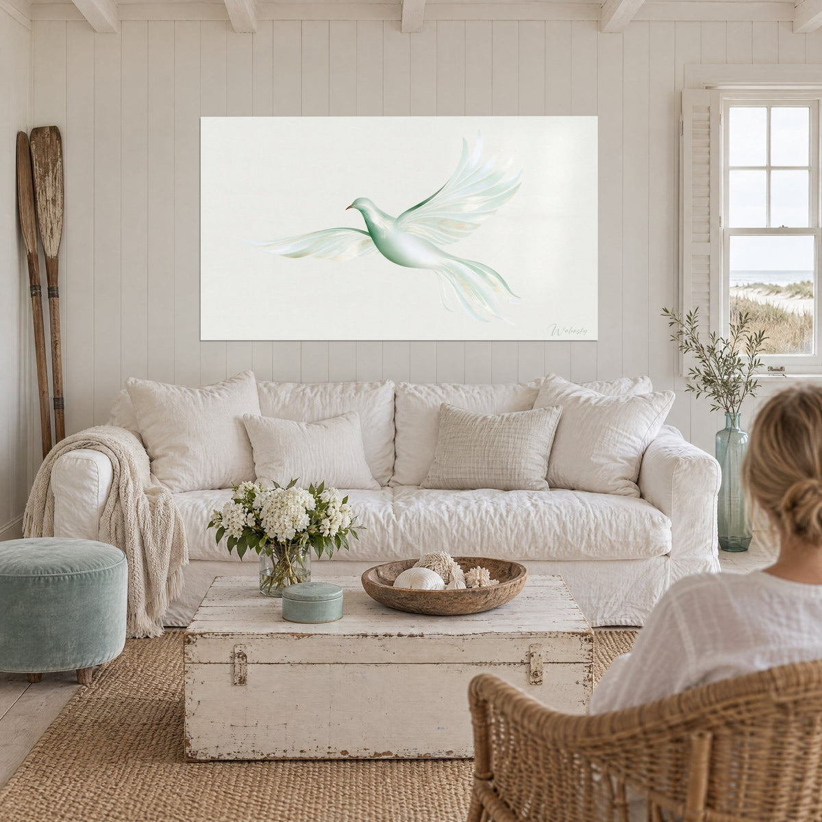 Quadro colomba bianca con ali verde salvia spiegate, riflessi dorati su sfondo crema, sopra un divano in un soggiorno luminoso