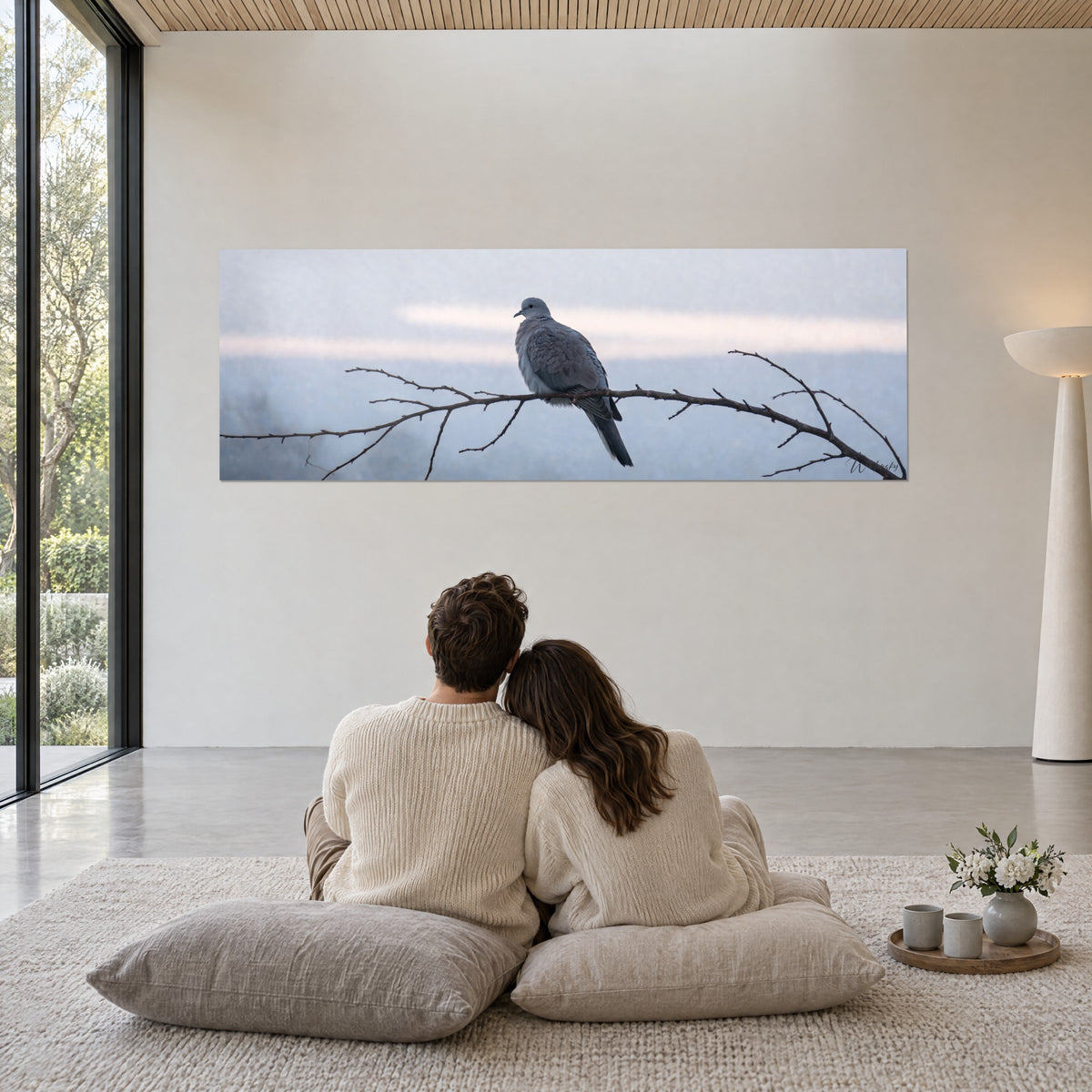 Gemälde ruhiger Vogel auf seiner Holzsitzstange, Graublau und rosé getöntes Cremeweiß, von hinten sitzendes Paar auf Kissen im Wohnzimmer
