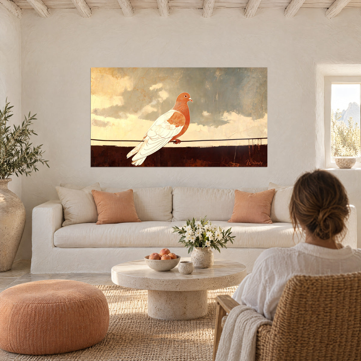 Tableau colombe blanche et terracotta sur un fil, ciel crème et gris, vue par une femme de dos au-dessus d'un canapé dans un salon lumineux