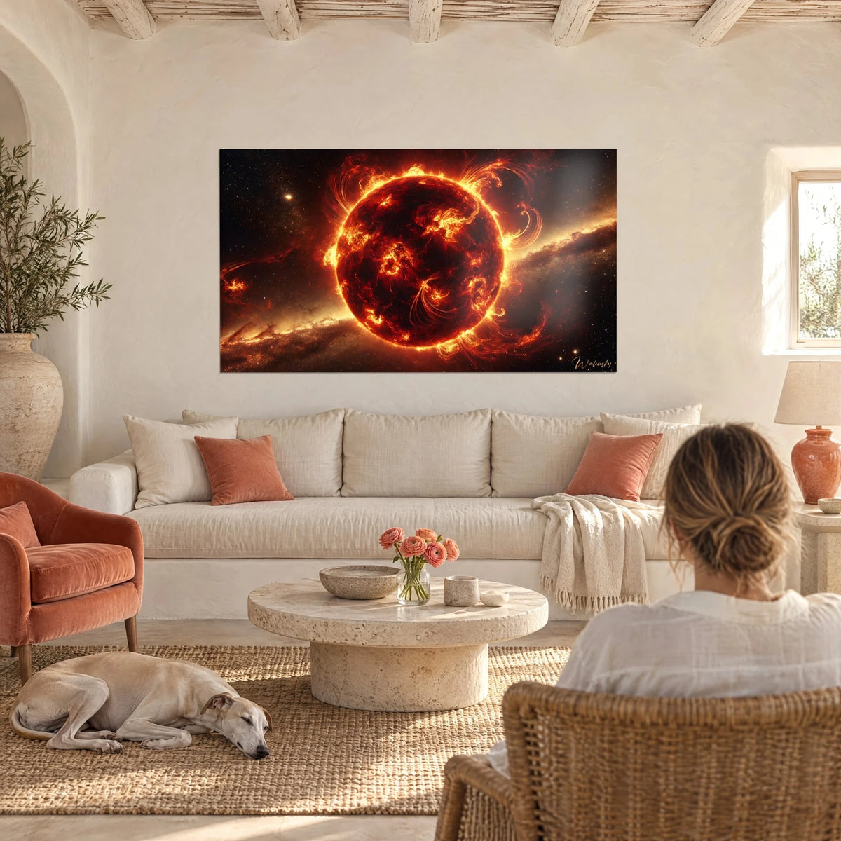 Schilderij vurige zon met oranje en rode vlammen op een zwarte ruimteachtergrond, vrouw van achteren en een windhond, boven een bank in een lichte woonkamer