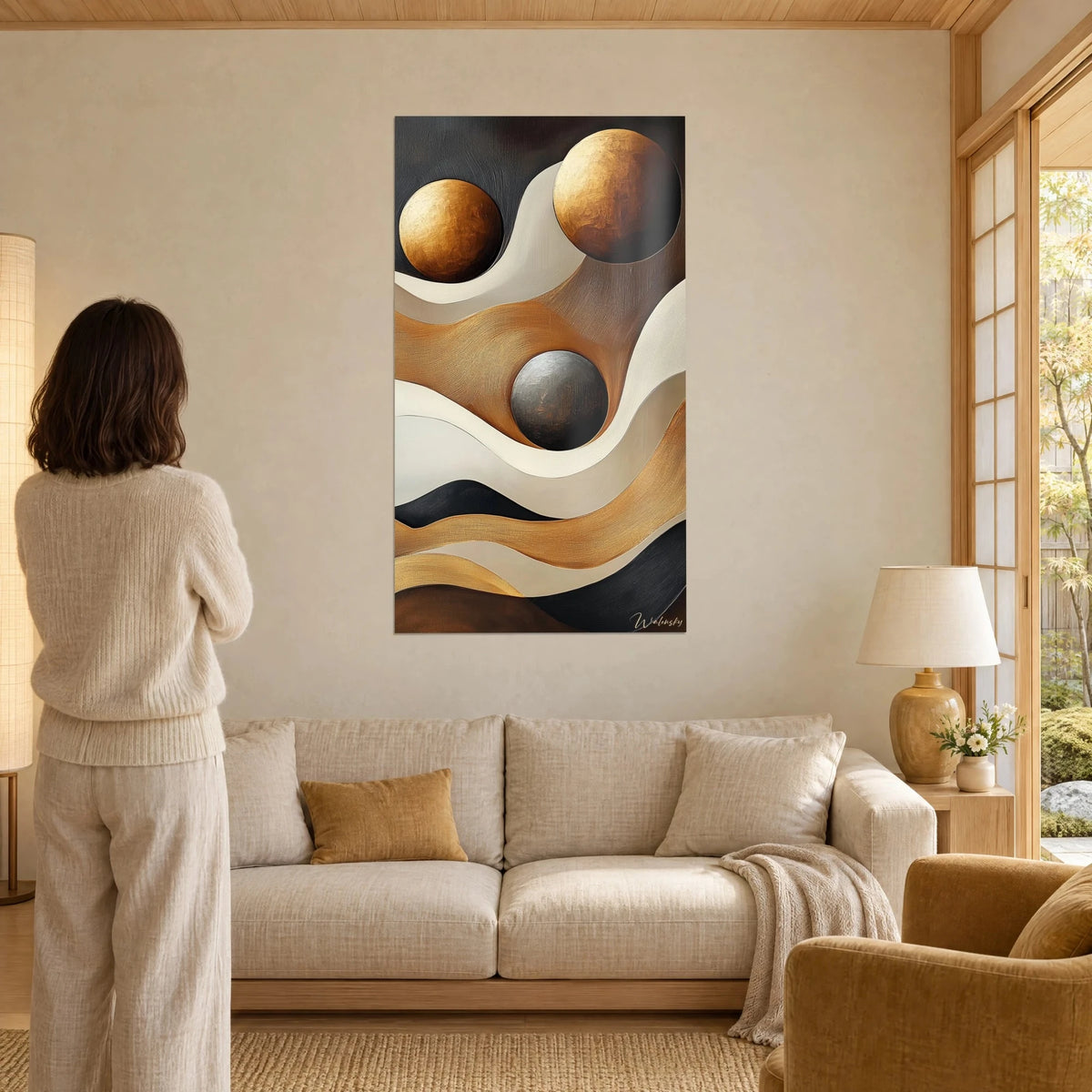 Cuadro con esferas doradas sobre olas crema y negras, textura ocre empastada, encima de un sofá en un salón luminoso