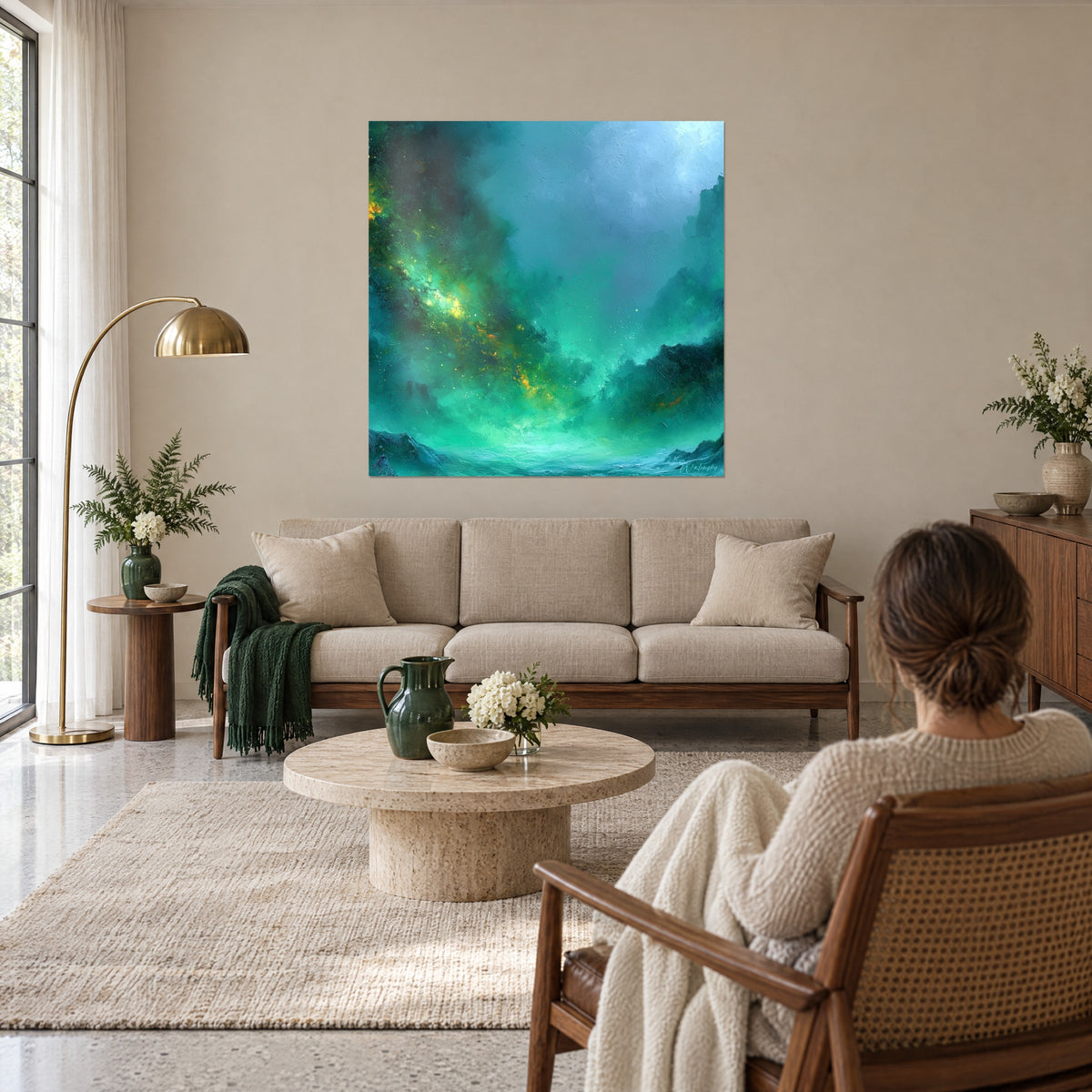 Gemälde Nebel-Galaxie in Smaragdgrün mit goldenen Streifen zwischen dunklen Klippen, eine Frau von hinten, über einem Sofa in einem hellen Wohnzimmer