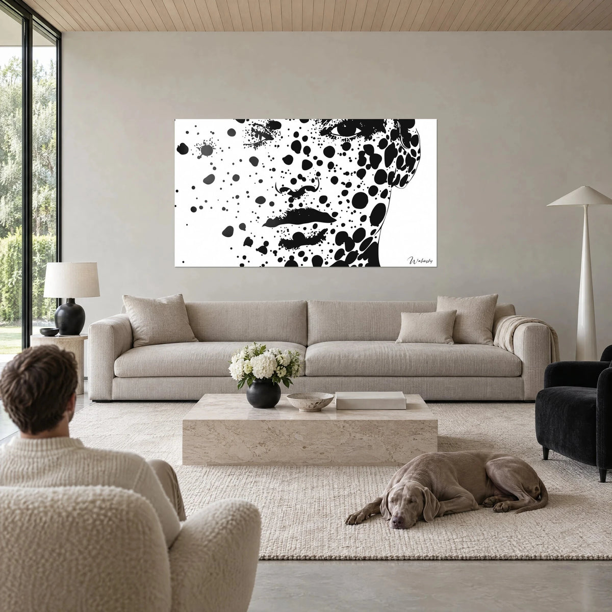 Gemälde eines Porträts aus schwarzen Tintenklecksen auf weißem Grund, intensiver Blick, über einem Sofa in einem hellen Wohnzimmer