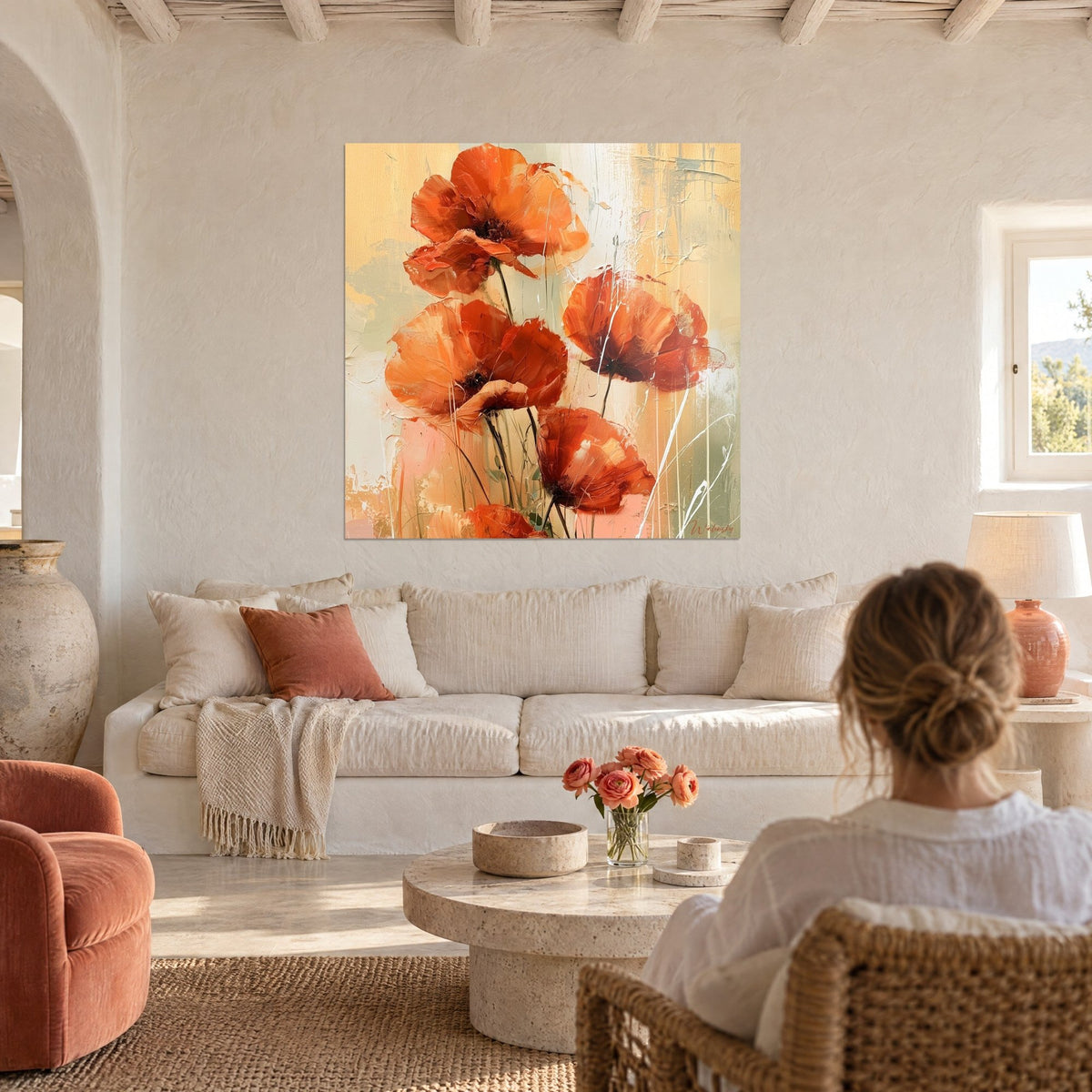 Schilderij felle oranje klaprozen met gekreukte bloemblaadjes, ocker- en salieachtergrond, gezien door een vrouw met losse knot boven een bank in een lichte woonkamer