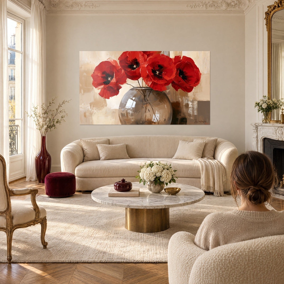 Schilderij boeket vuurrode klaprozen in een ronde rookglazen vaas, beige achtergrond, vrouw van achteren, boven een bank in een lichte woonkamer