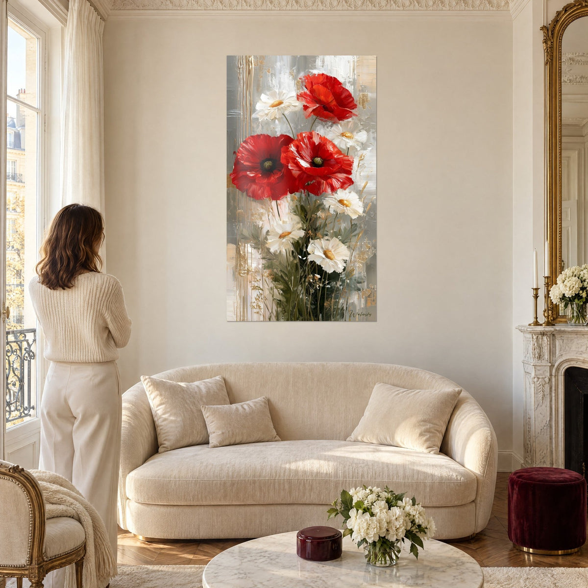 Tableau coquelicots écarlates et marguerites ivoire, coulures dorées sur fond gris, femme de dos, au-dessus d'un canapé dans un salon lumineux