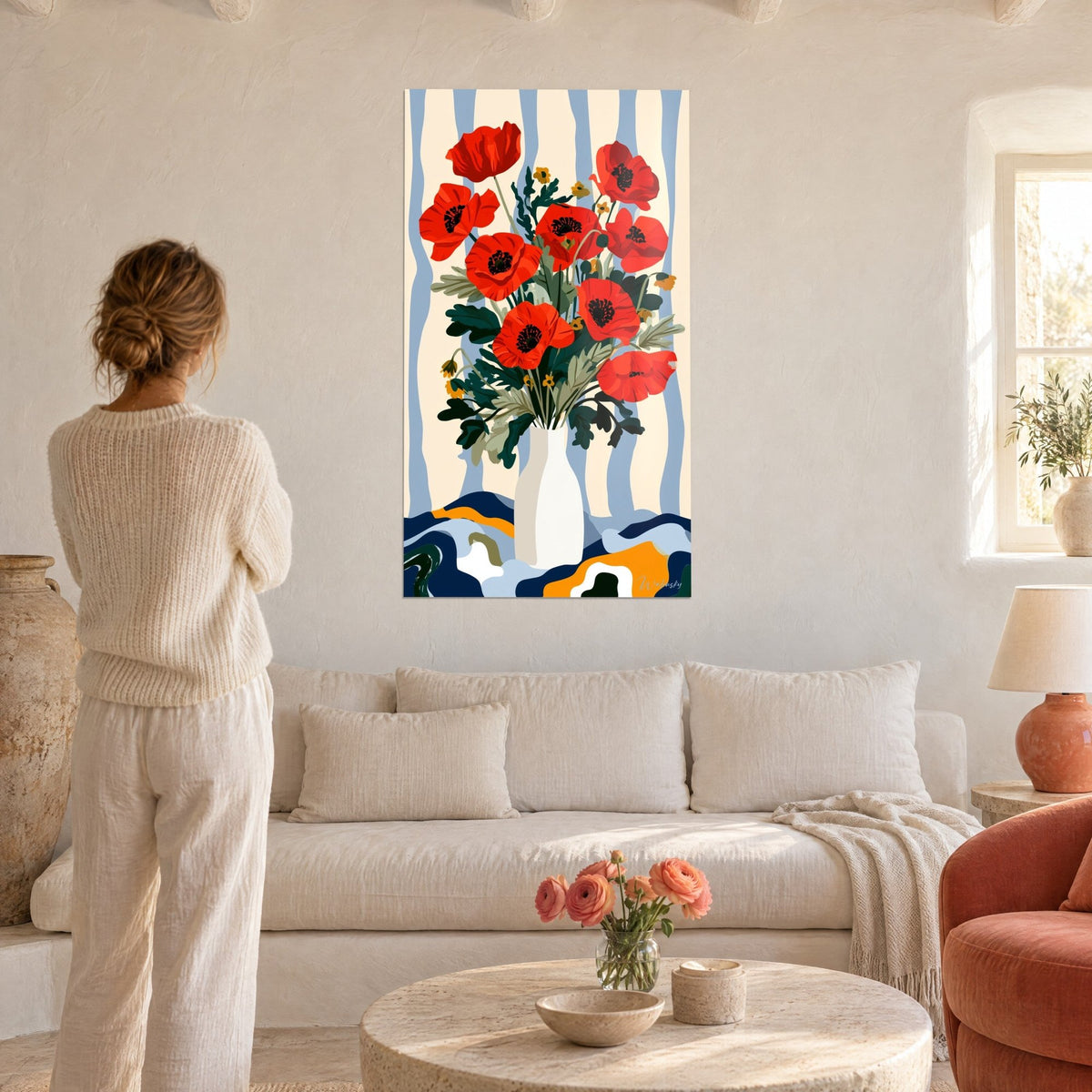 Tableau bouquet de coquelicots rouge vif sur fond rayé bleu pâle, femme de dos, au-dessus d'un canapé dans un salon lumineux