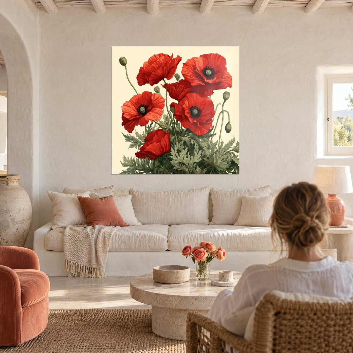 Tableau coquelicots écarlates et boutons vert sauge sur fond crème, une femme chignon de dos, au-dessus d'un canapé dans un salon lumineux