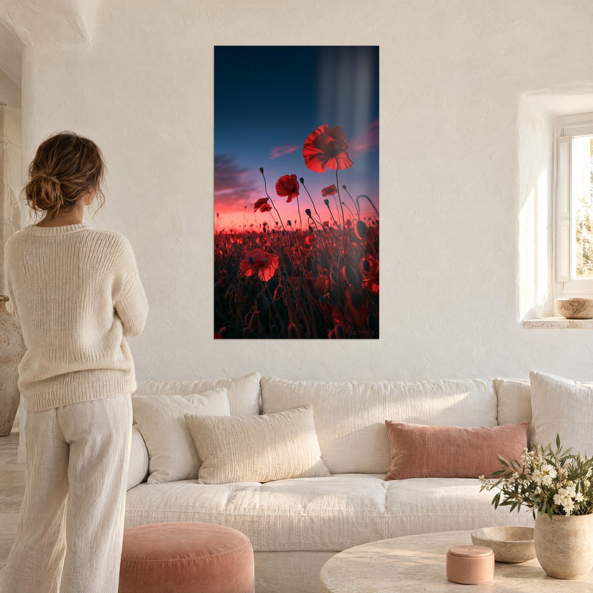 Tableau coquelicots écarlates dressés sur ciel bleu nuit et horizon rose, femme de dos, au-dessus d'un canapé dans un salon lumineux