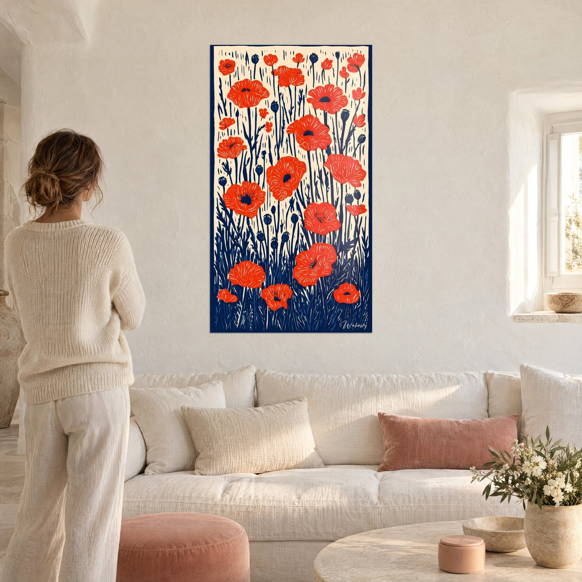 Tableau champ de coquelicots rouge vermillon, tiges bleu marine gravées sur fond crème, au-dessus d'un canapé dans un salon lumineux