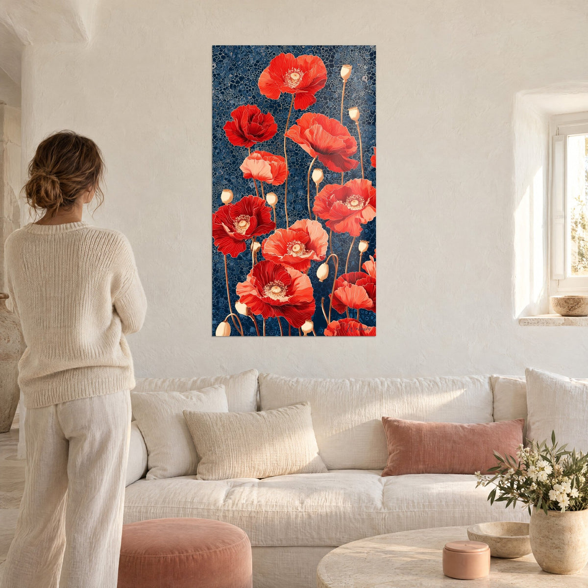 Wall art red poppies on a cellular navy blue background, golden seed pods, woman seen from behind, above a sofa in a bright living room