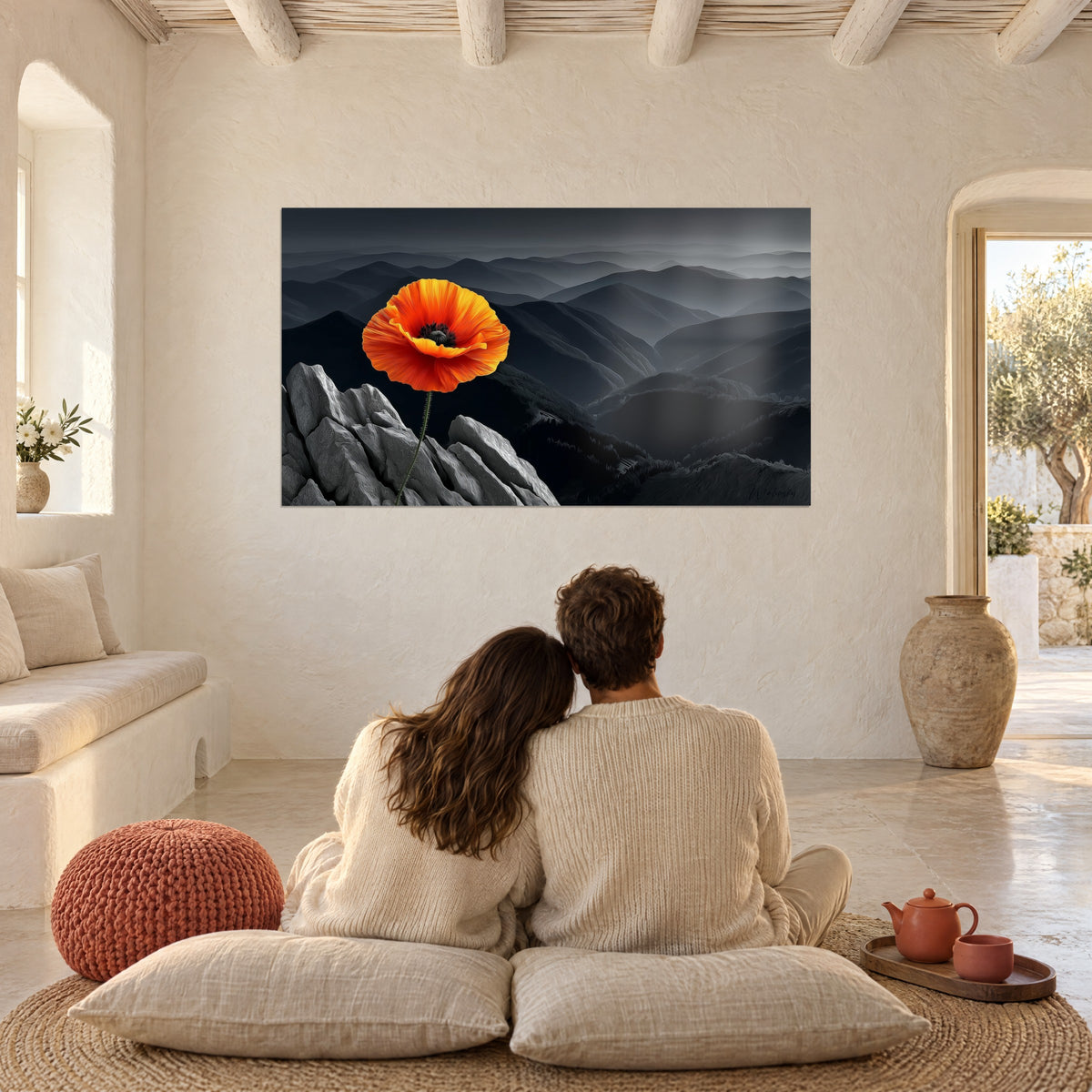 Gemälde Strahlend orangefarbener Mohn vor anthrazitfarbenem Bergpanorama, eng umschlungenes Paar von hinten auf Kissen, rostfarbener Pouf, mediterranes Haus