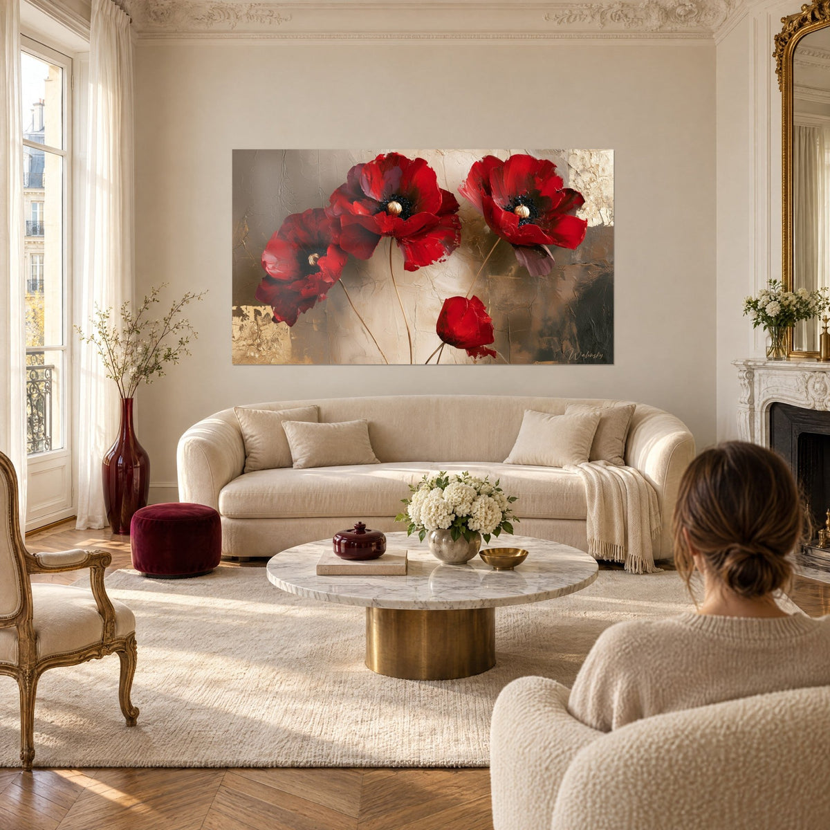 Tableau coquelicots écarlates aux cœurs dorés sur fond craquelé beige et or, une femme de dos, au-dessus d'un canapé dans un salon lumineux