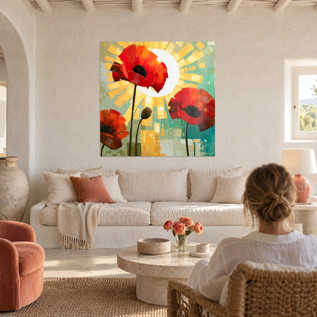 Tableau coquelicots écarlates et soleil blanc rayonnant sur fond turquoise, femme chignon de dos, au-dessus d'un canapé dans un salon lumineux