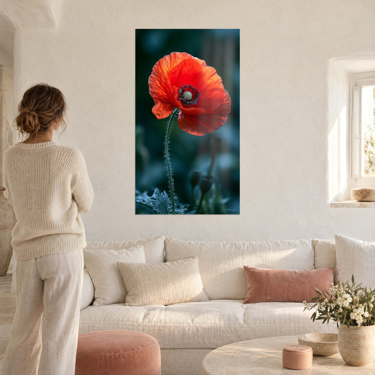 Cuadro amapola naranja de pétalos arrugados sobre fondo verde oscuro, tallo erizado, encima de un sofá en un salón luminoso
