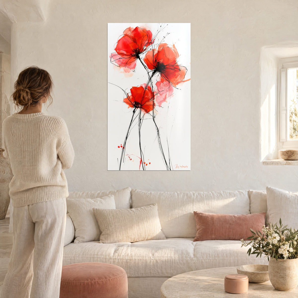 Quadro trittico di papaveri rosso vivo e corallo, steli a inchiostro nero, una donna di spalle sopra un divano in un soggiorno luminoso