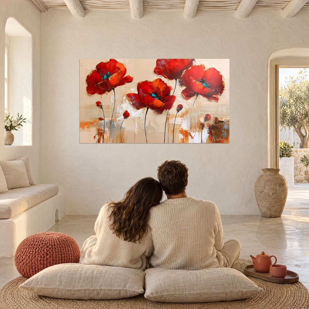 Wall art of large coral-red flowers with turquoise pistils, textured beige background, facing a couple seated on cushions
