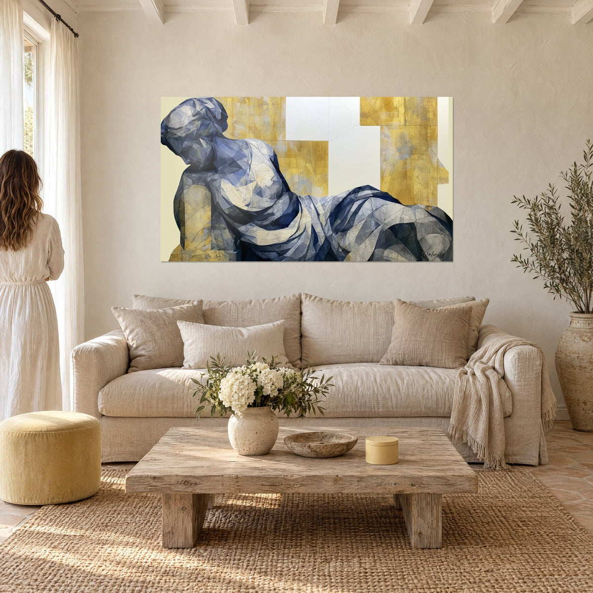 Tableau statue allongée aux drapés bleu nuit et or, tête penchée sur l'épaule, au-dessus d'un canapé dans un salon lumineux