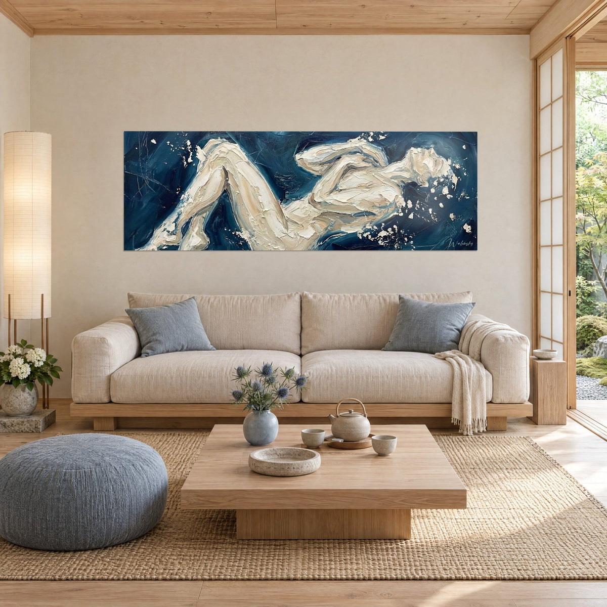 Wall art of an elongated silhouette in ivory and beige impasto on navy blue background, with splashes, above a sofa in a bright living room