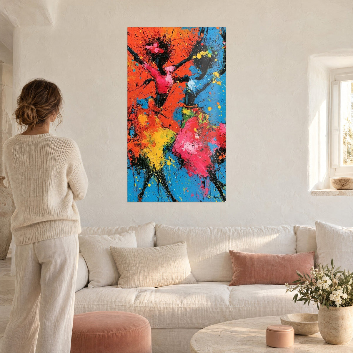 Tableau deux danseuses éclaboussées de jaune, rose et orange sur fond bleu, au-dessus d'un canapé dans un salon lumineux