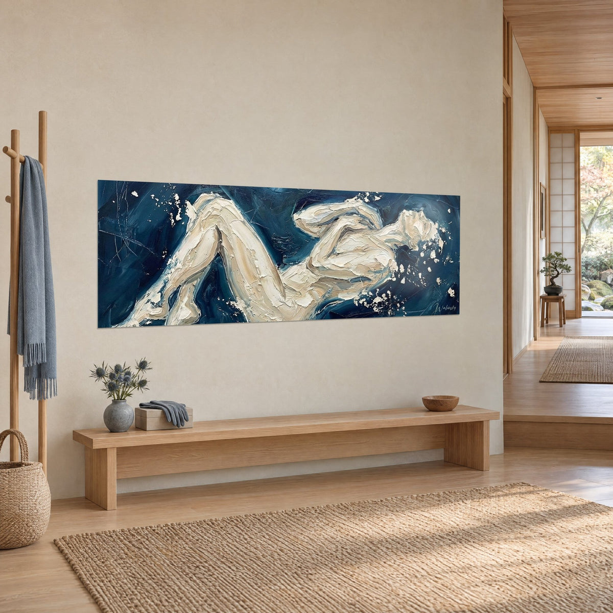 Wall art of a nude body in thick cream paint on midnight blue, knees drawn up, hung near a light wood bench and a hallway