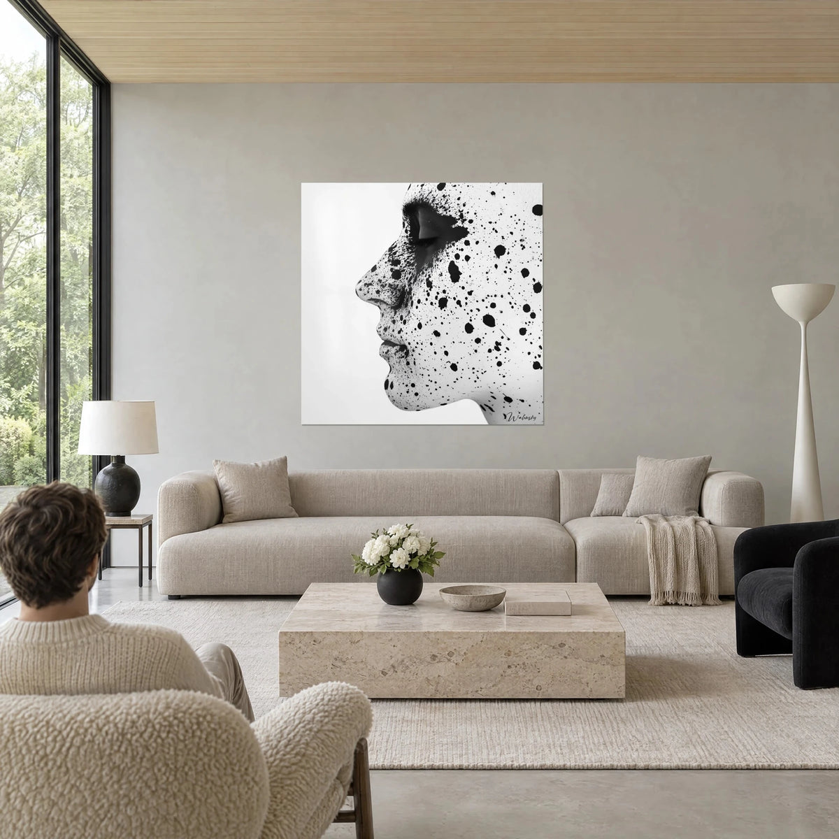 Gemälde Frauenprofil mit schwarzen Tintenspritzern auf weißer Haut, zwei Personen von hinten, über einem Sofa in einem hellen Wohnzimmer