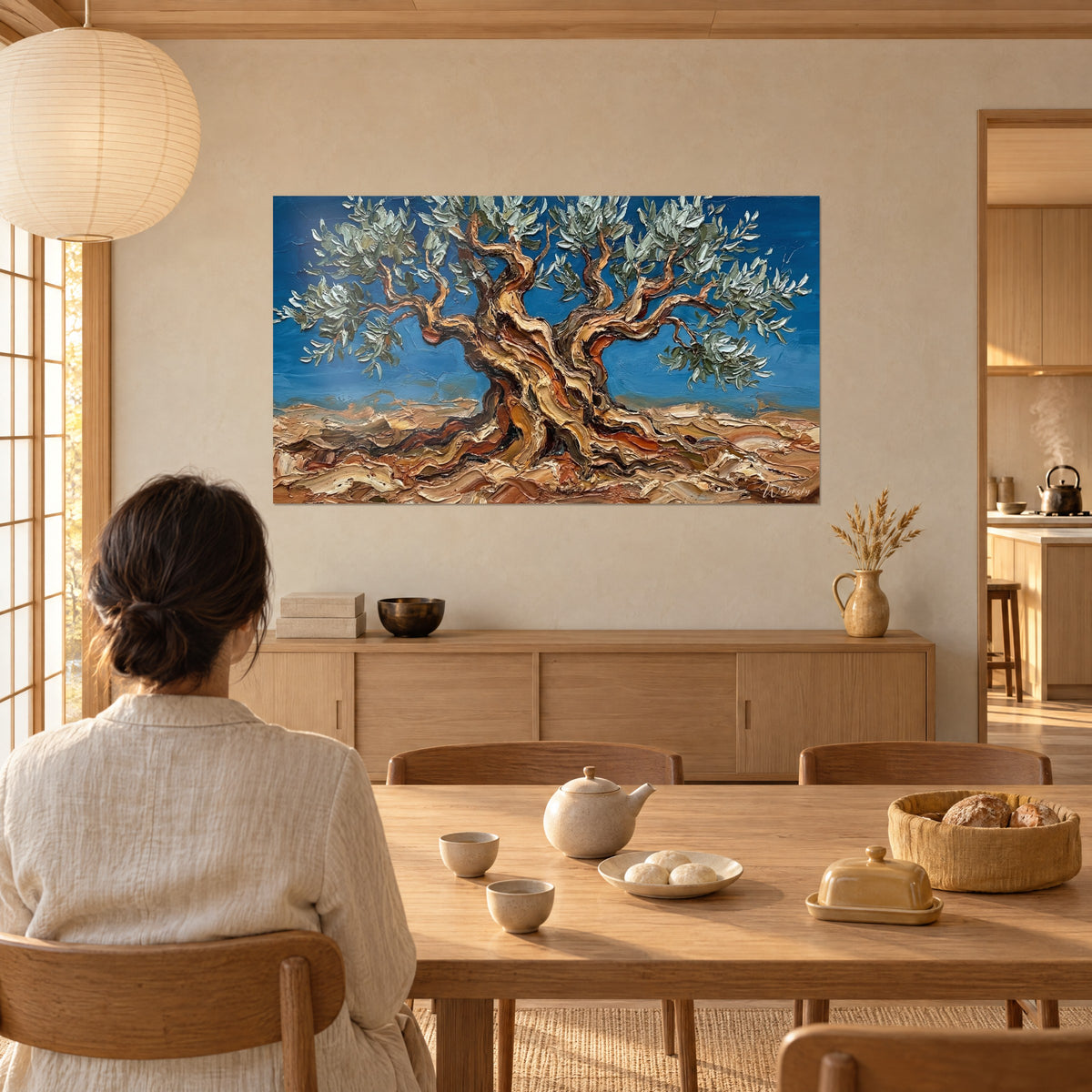 Tableau vieil olivier aux branches sinueuses brun cuivré, feuillage argenté, ciel bleu roi, contemplé par une femme de dos, salle à manger japandi