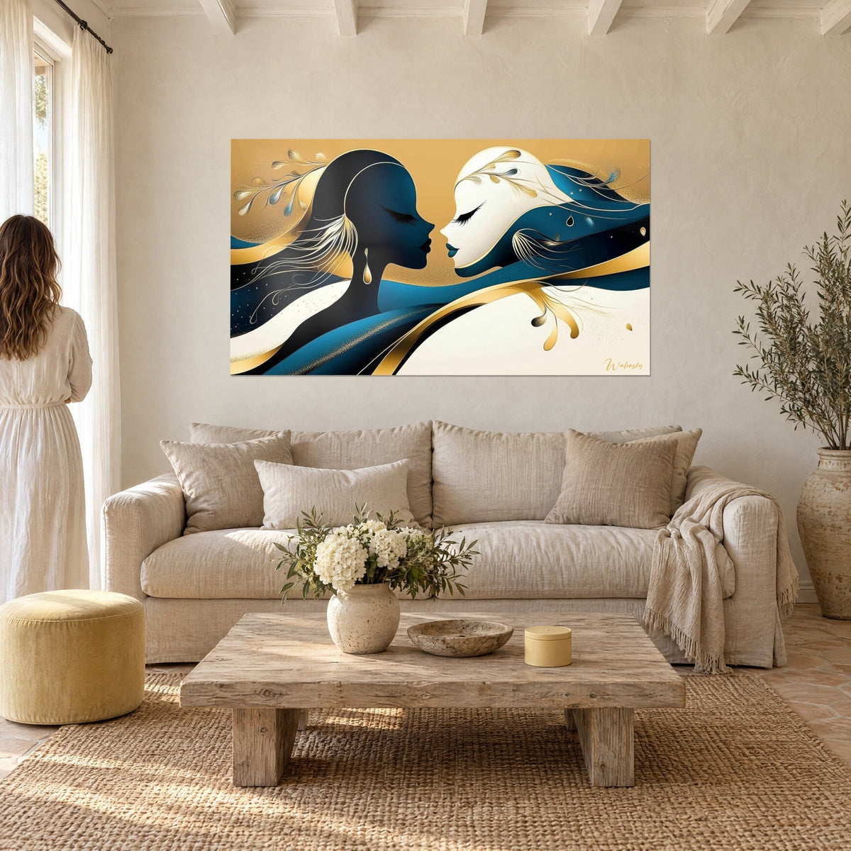 Wall art two profile faces facing each other, midnight blue and ivory, golden ribbons, a woman seen from behind, above a sofa in a bright living room