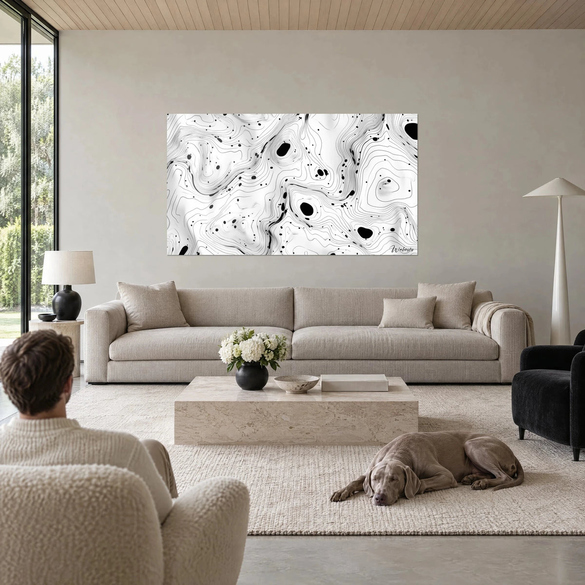 Gemälde Kartenmotiv mit feinen schwarzen Linien und Tintenflecken auf weißem Grund, zwei Personen von hinten, grauer Hund, über einem Sofa in einem hellen Wohnzimmer