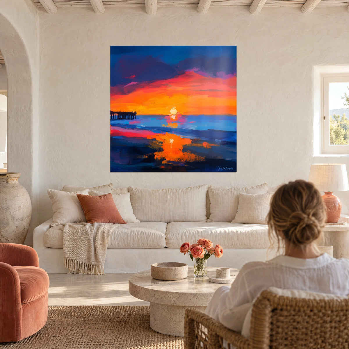 Quadro tramonto arancio e corallo su mare blu cobalto, molo scuro a sinistra, sopra un divano in un soggiorno luminoso