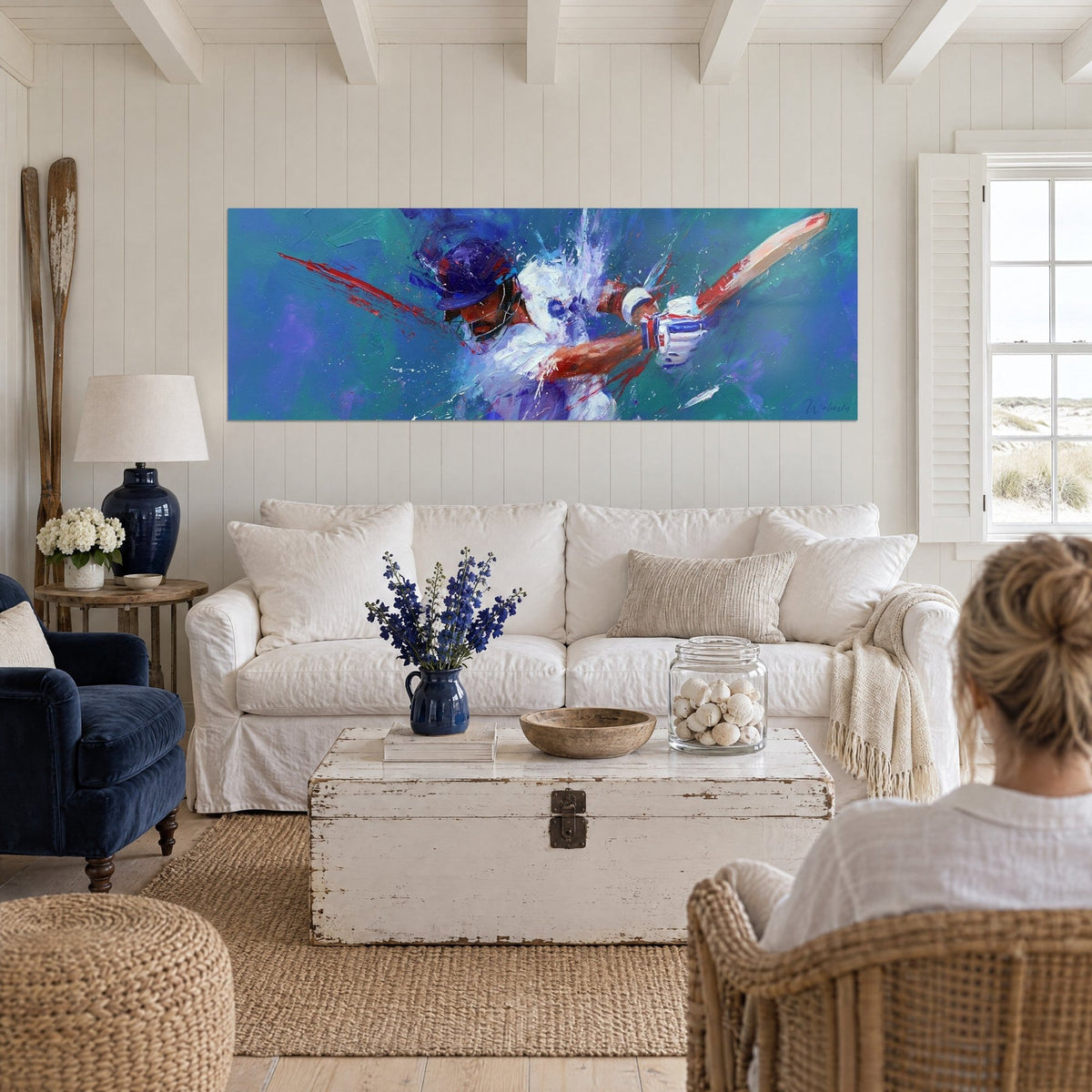 Quadro battitore di cricket con casco, striature scarlatte su fondo turchese e viola, due donne di spalle, sopra un divano in un soggiorno luminoso