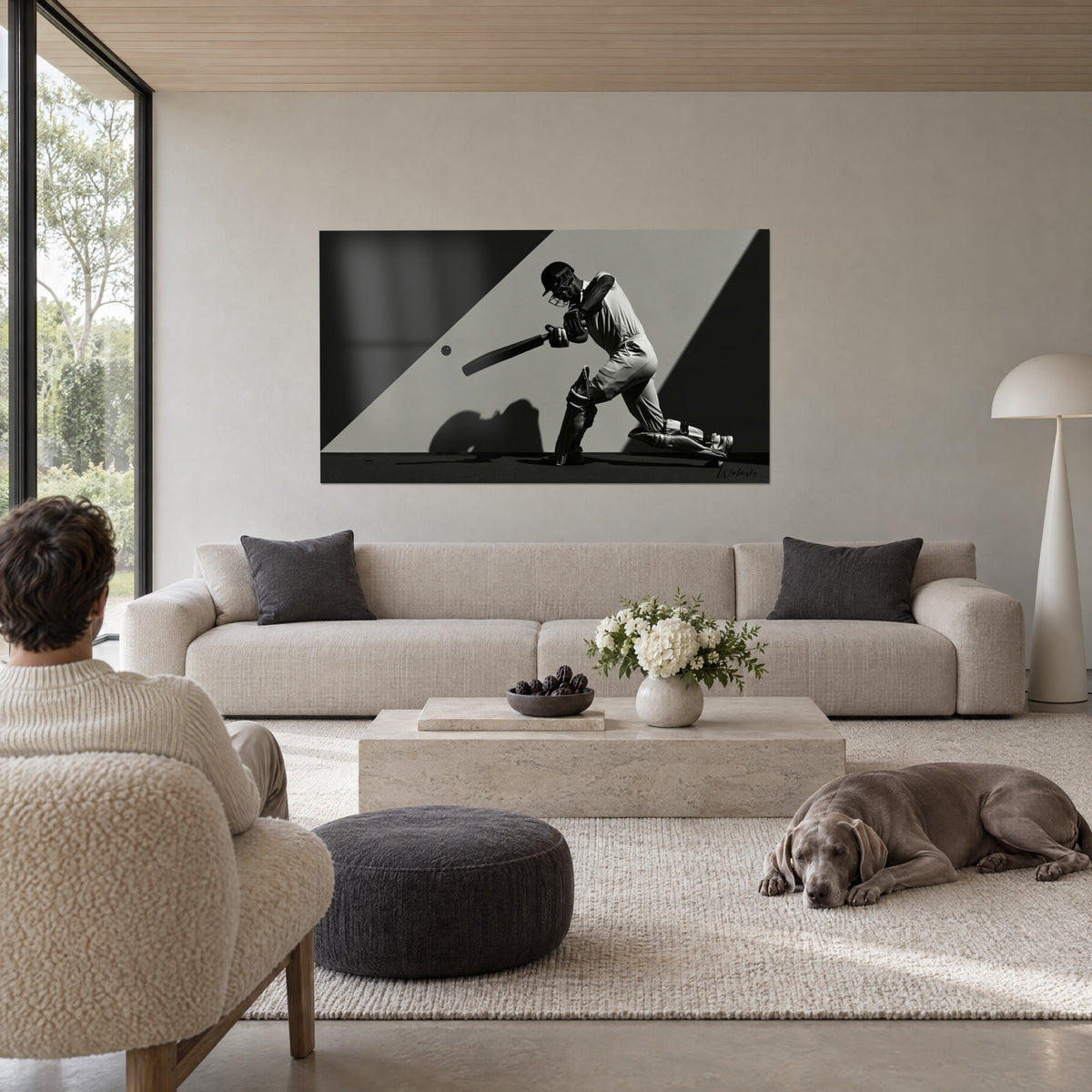 Schilderij van een helmdragende cricketbatsman midden in de slag, zwart en grijs, geworpen schaduw, boven een bank in een lichte woonkamer