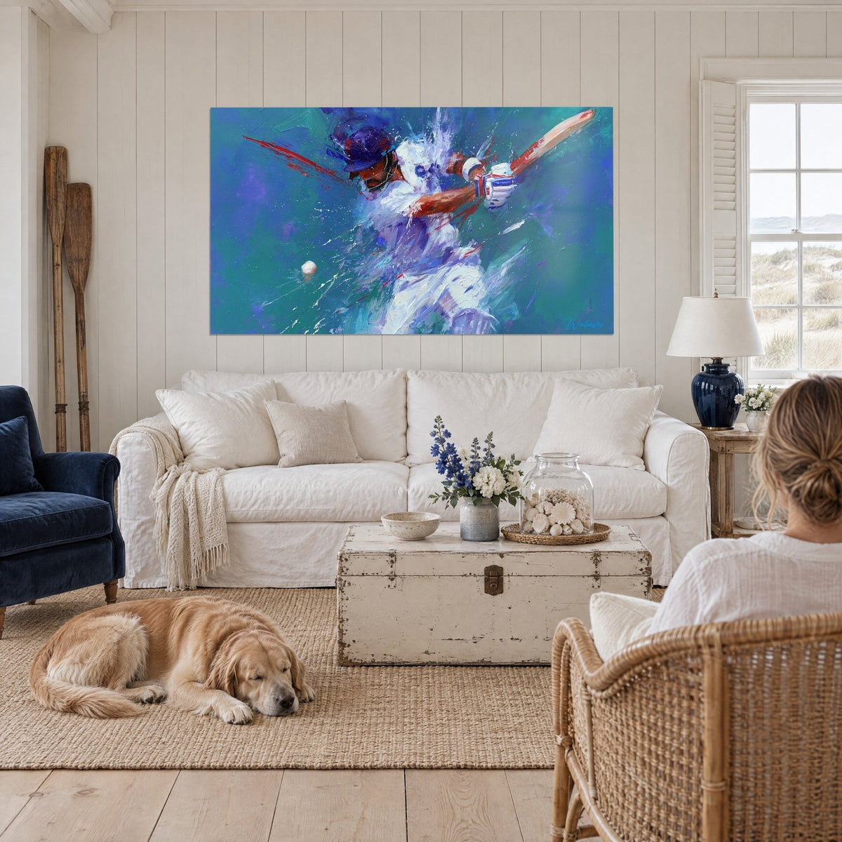 Tableau batteur de cricket en blanc éclaboussé de rouge sur fond turquoise, balle blanche, au-dessus d'un canapé dans un salon lumineux