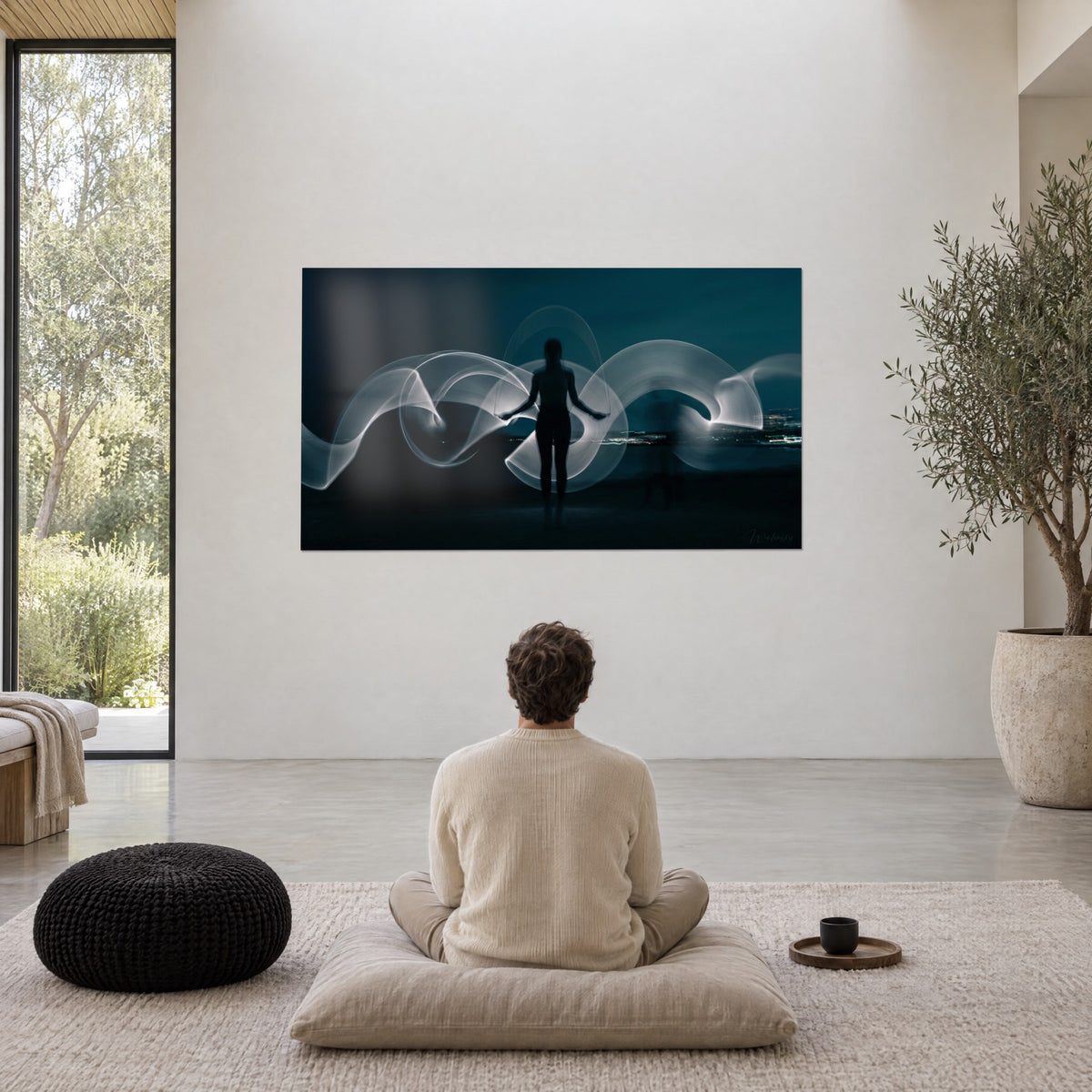 Tableau mouvement de lumière en ondes argentées autour d'une silhouette sombre, bleu nuit profond, face à un homme méditant au salon