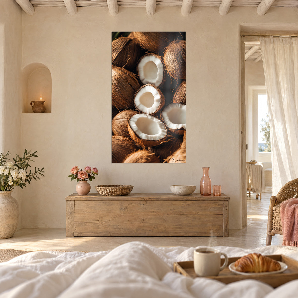 Cuadro de cocos entreabiertos, pulpa blanca y fibras castañas, en la pared de un dormitorio luminoso, sobre una cama deshecha