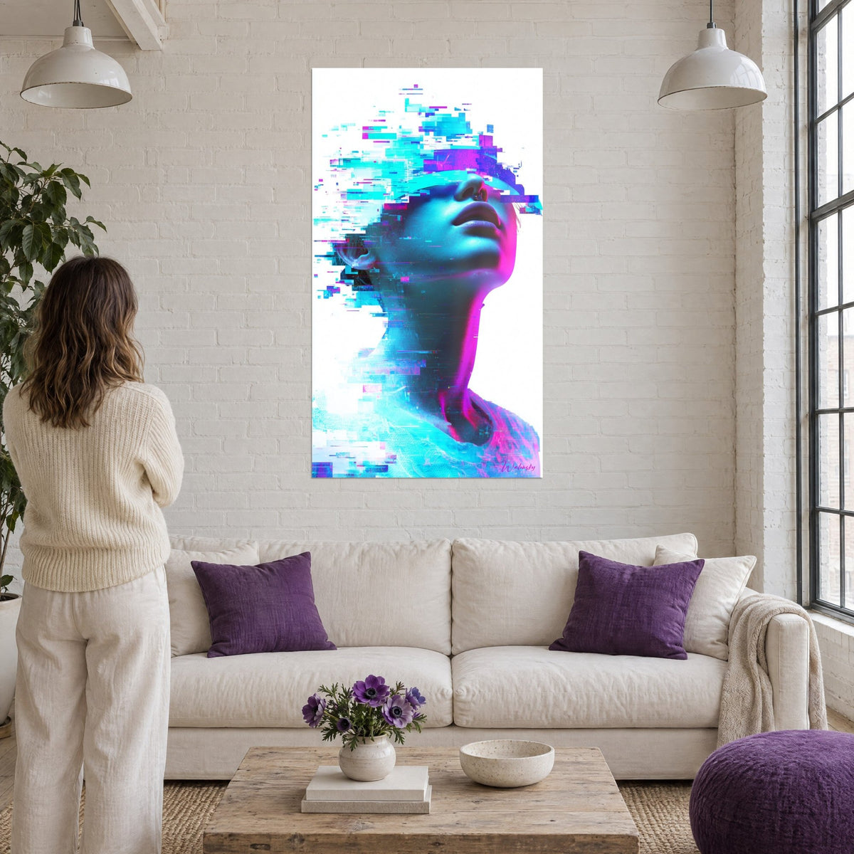 Tableau visage numérique levé vers le ciel, pixels turquoise et magenta, femme de dos, au-dessus d'un canapé dans un salon lumineux
