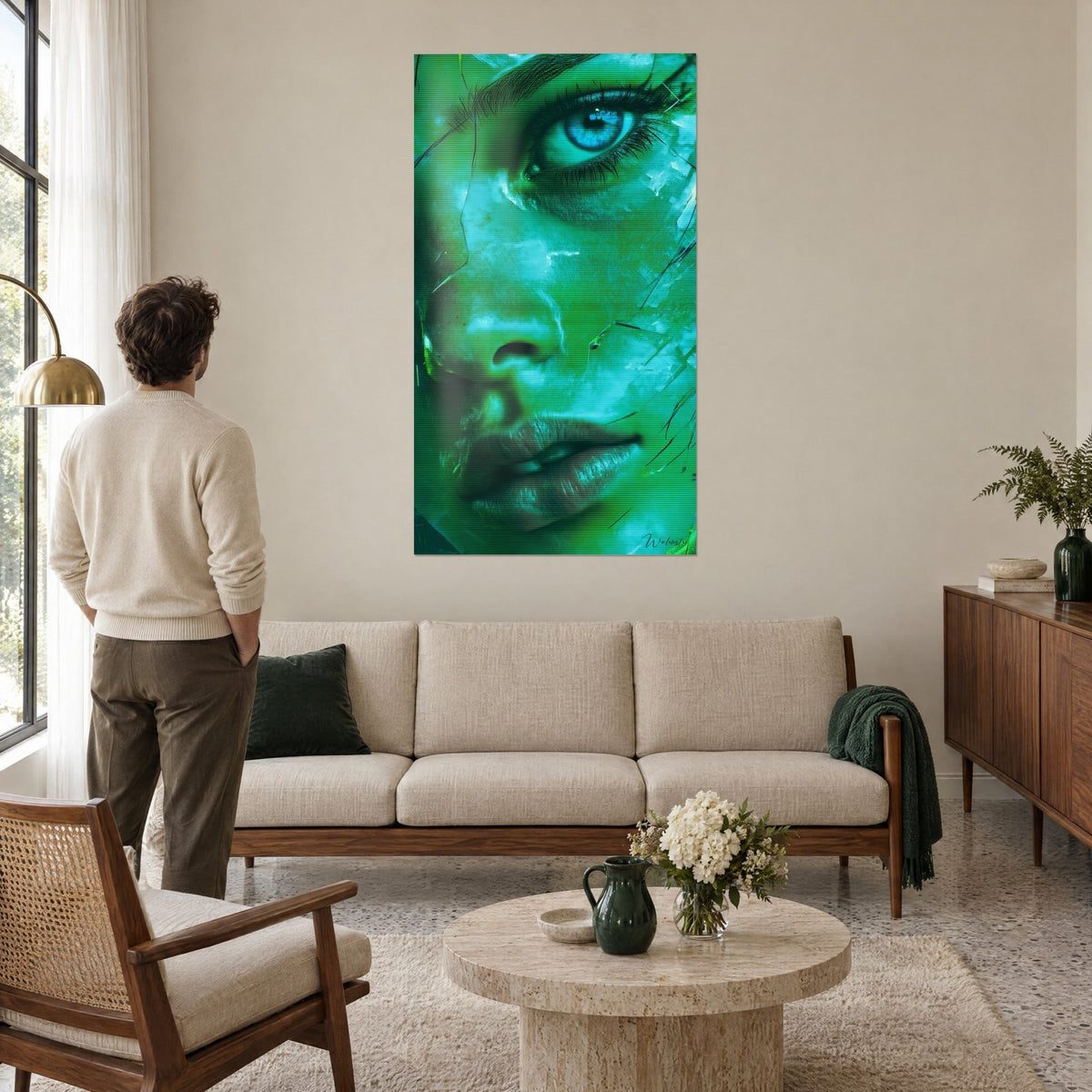 Tableau portrait vert émeraude, œil bleu glacier et lèvres striées, regardé par un homme en pull crème au-dessus d'un canapé dans un salon lumineux