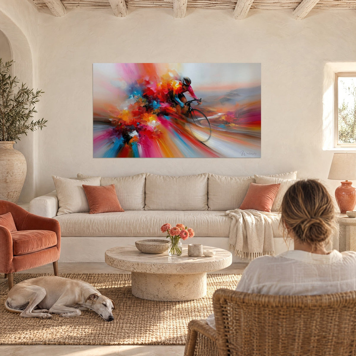 Wall art cyclist racing through an explosion of red and pink, above a sofa with a greyhound in a bright living room