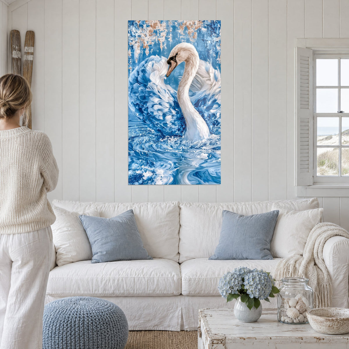 Tableau cygne blanc au long cou courbé, ailes bleu marine en volutes sur un fond turquoise écaillé, au-dessus d'un canapé dans un salon lumineux