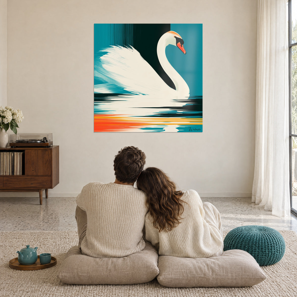 Cuadro cisne en planos marfil, turquesa y naranja vivo, frente a una pareja abrazada de espaldas sobre cojines en un salón