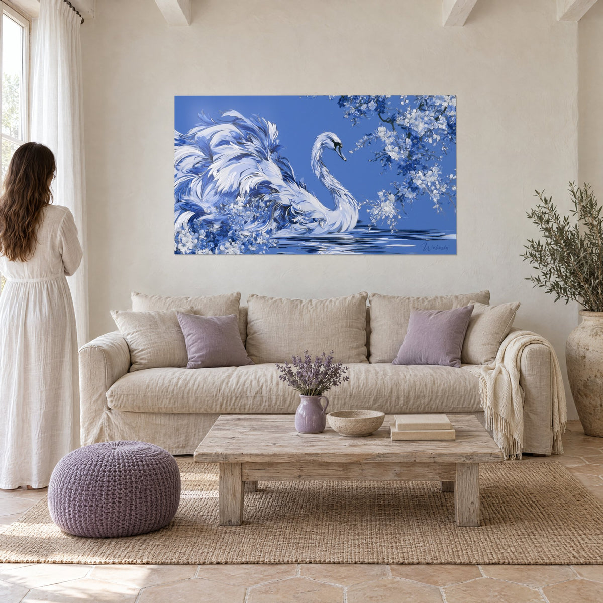 Tableau cygne ivoire au plumage tourbillonnant, fond bleu cobalt et fleurs blanches, au-dessus d'un canapé dans un salon lumineux