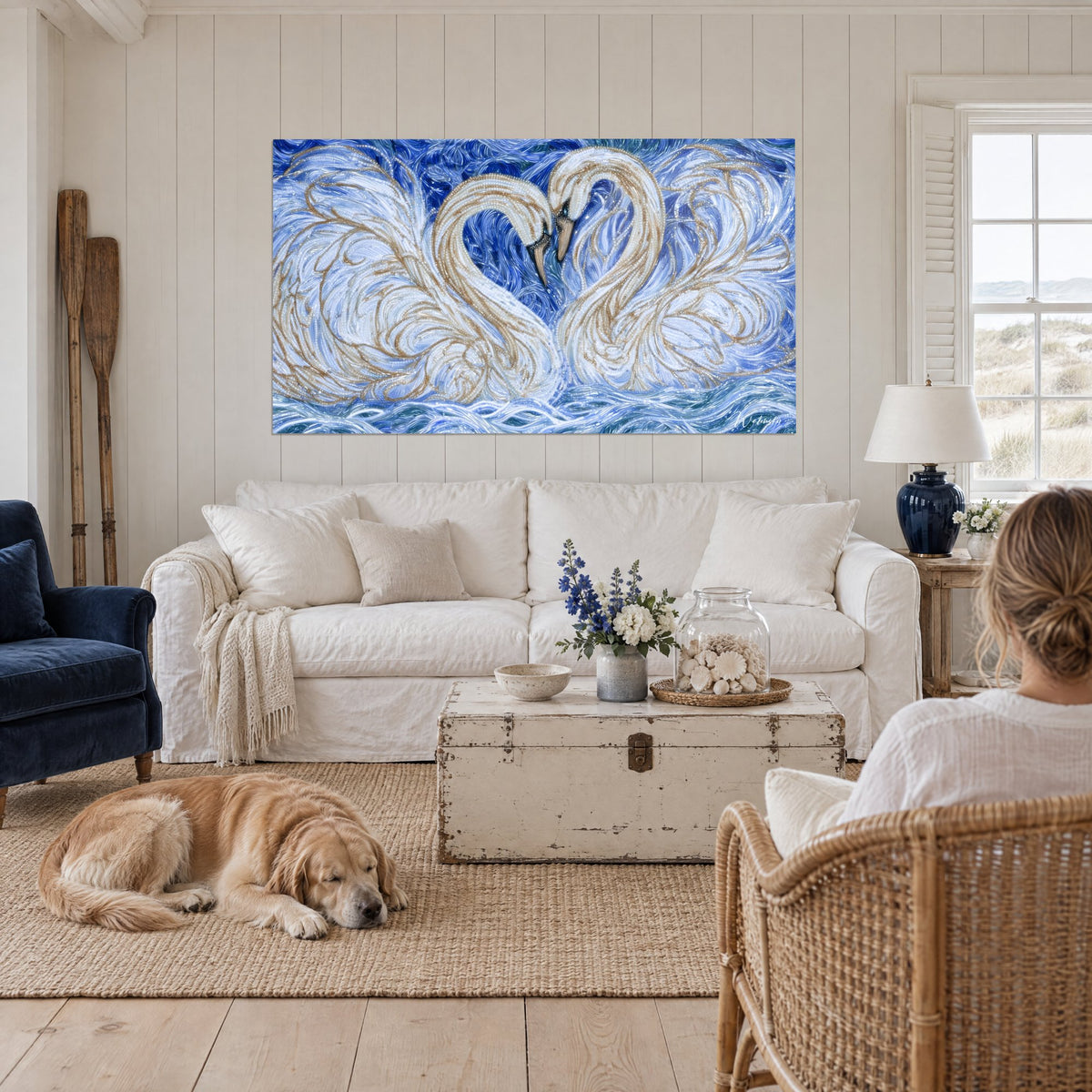 Quadro cigni bianchi con colli a forma di cuore, piume avorio e oro su onde blu cobalto, sopra un divano in un soggiorno luminoso