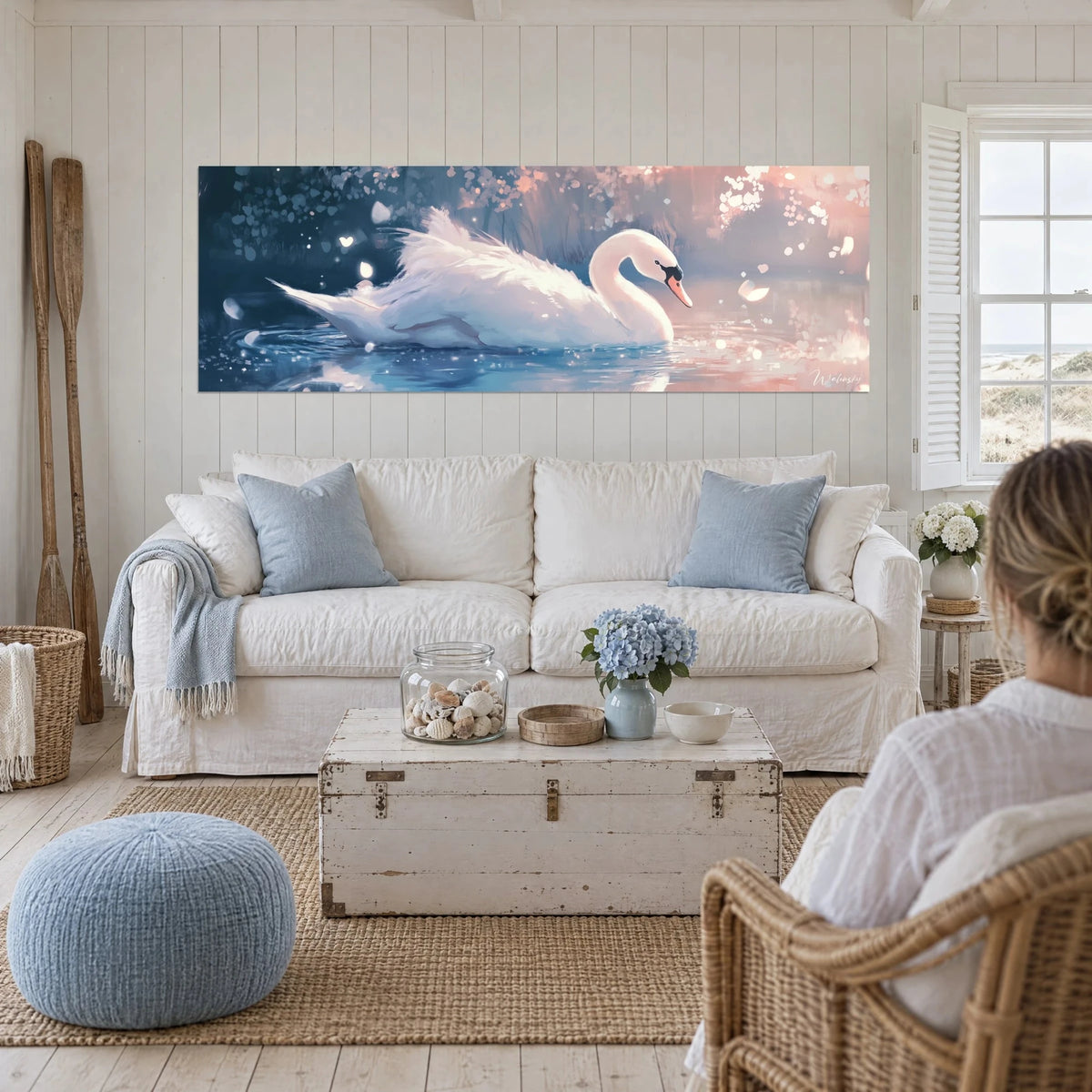 Wall art of a white swan gliding over midnight-blue water, pale pink reflections, above a sofa in a bright living room