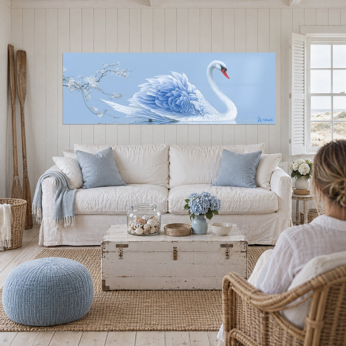 Tableau cygne blanc aux plumes bleu azur et bec rouge, branche fleurie, au-dessus d'un canapé dans un salon lumineux