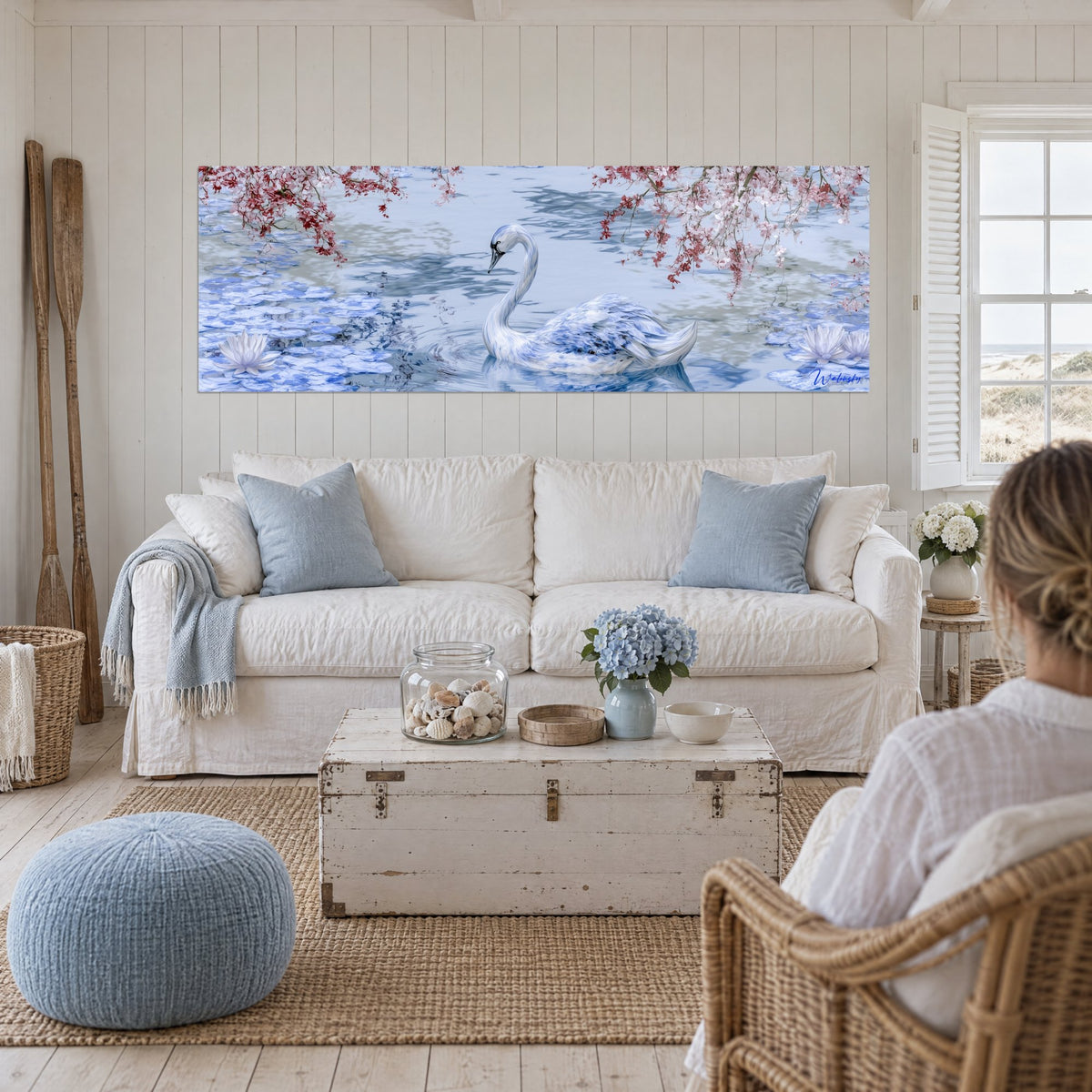 Tableau cygne bleu porcelaine glissant sur l'eau pâle, branches de cerisier rose et nénuphars, au-dessus d'un canapé dans un salon lumineux