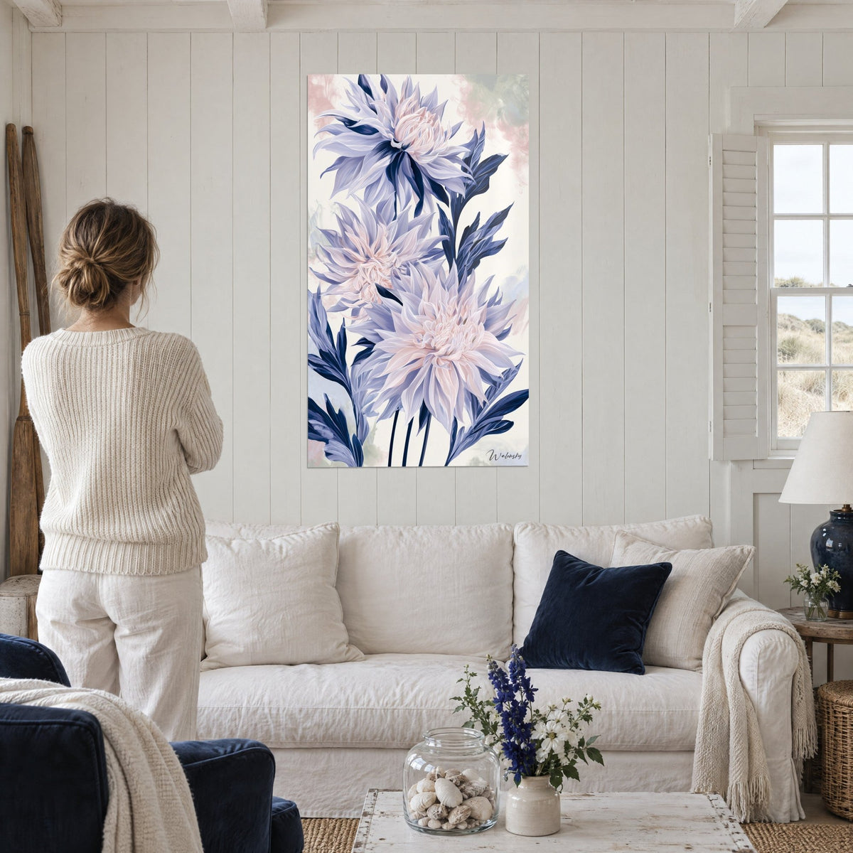 Cuadro de dalias lavanda con hojas índigo, una persona de espaldas delante, sobre un sofá en un salón luminoso