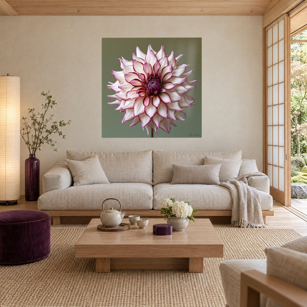 Tableau dahlia aux pétales blancs ourlés de fuchsia sur fond vert sauge, au-dessus d'un canapé dans un salon lumineux